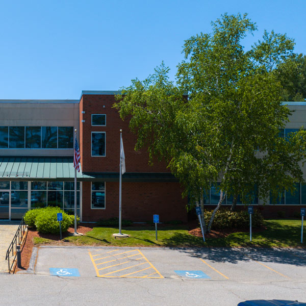 A building surrounded by a parking lot and trees, showcasing a blend of architecture and nature.